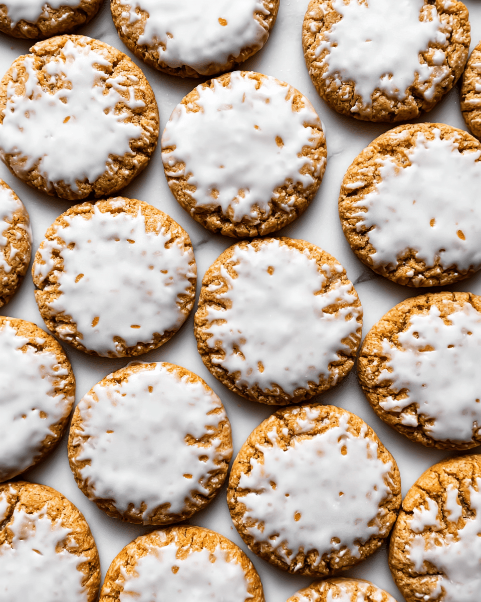 The image shows a close-up view of many round cookies placed tightly together on a white marbled surface. Each cookie has one main visible layer, a golden brown baked base with a slightly rough texture. The top of each cookie is unevenly covered with a thin white icing layer, creating a contrast with the golden cookie. The icing looks smooth but irregular, with some parts thicker and other parts thinner, revealing the cookie's surface underneath in a cracked pattern. The cookies are evenly spread across the frame without any other objects visible. photo taken with an iphone --ar 4:5 --v 7