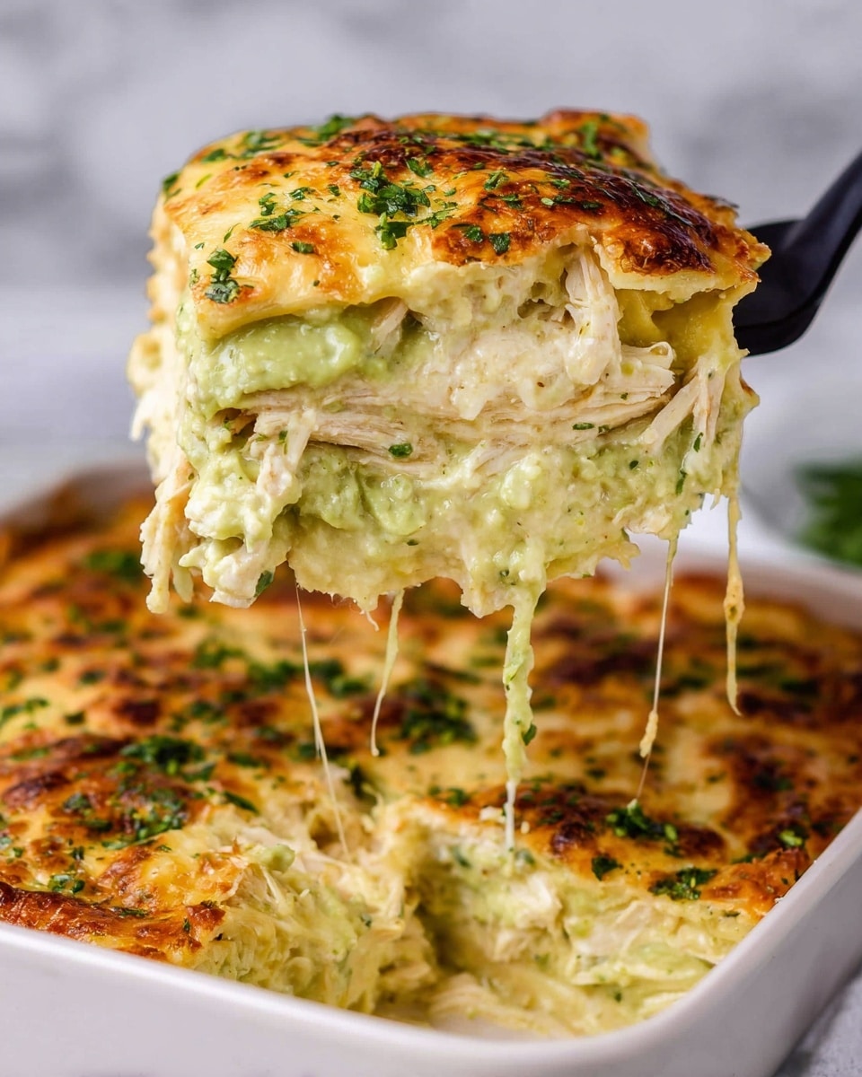 A close-up view of a thick, square slice of layered casserole being lifted by a black spatula, showing four main layers: the top layer is a golden-brown, slightly crispy cheese and herb crust with green flecks; under that is a creamy pale green layer, likely avocado or a green sauce; followed by a softer, light yellow cheese or sauce layer; and at the bottom, a mix of shredded white chicken meat and melted cheese stretching in strings. The casserole sits in a white ceramic baking dish on a white marbled surface, with chopped green herbs sprinkled on top. Photo taken with an iphone --ar 4:5 --v 7