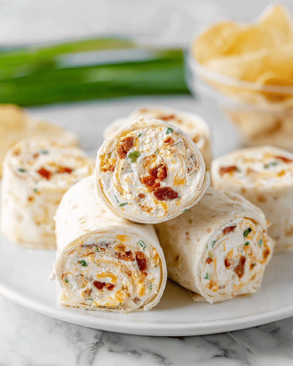A close-up of several cream cheese pinwheel wraps stacked on a white plate on a white marbled surface. Each wrap is made of a soft, pale tortilla rolled with a thick, creamy white layer filled with small bits of orange cheddar cheese, red bacon pieces, and green herbs, all visible in spiral layers. The texture of the tortilla looks soft and slightly fluffy, while the filling appears rich and creamy. In the blurry background, two green onions and a clear bowl with light-colored chips are present, adding color contrasts. Photo taken with an iphone --ar 4:5 --v 7