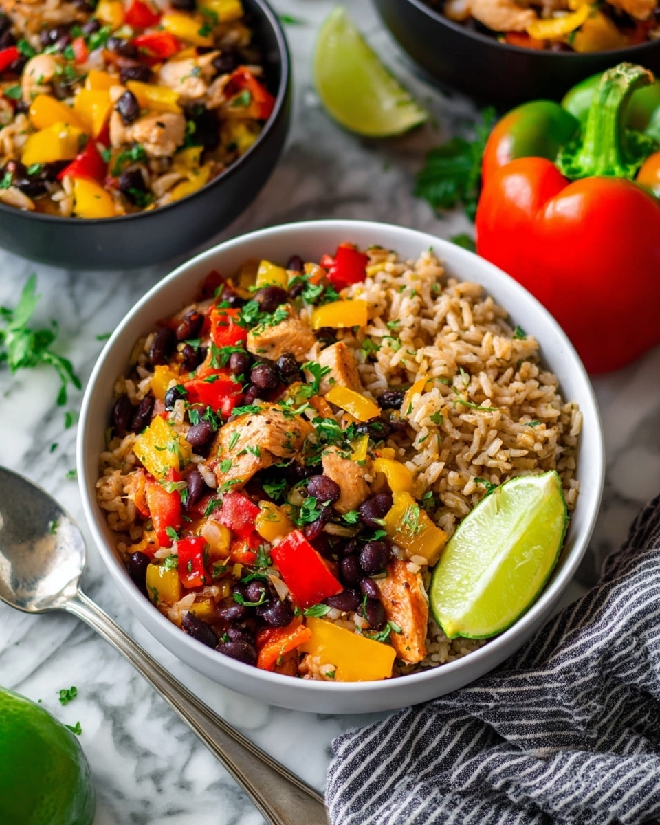 A bowl of colorful rice dish is full of different bright ingredients. The bottom layer is fluffy brown rice mixed with black beans, visible throughout. On top of this, there are chunks of red and yellow bell peppers, pieces of cooked chicken with a light brown color, and finely chopped green herbs spread evenly. A slice of lime leans on one side of the bowl, adding a fresh green touch. The bowl is white and sits on a white marbled surface, with a silver spoon resting near it. In the background, there are other similar bowls and fresh whole bell peppers, with a gray and white striped cloth beside the bowl. photo taken with an iphone --ar 4:5 --v 7