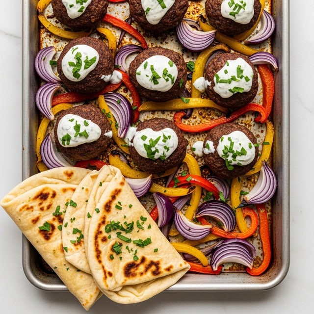The image shows a metal baking tray filled with several dark brown meatballs, each topped with a creamy white sauce and sprinkled with green herbs. Beneath and around the meatballs are colorful strips of cooked vegetables, including red, yellow, and orange bell peppers, and slices of purple onion, all soft and slightly glossy. In the bottom left corner, there are two folded pieces of light golden-brown flatbread with darker grilled spots and a light sprinkle of green herbs. The whole tray sits on a white marbled surface. Photo taken with an iphone --ar 4:5 --v 7
