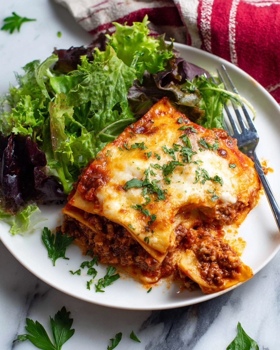A white plate holds a serving of lasagna with three visible layers: the bottom pasta layer is golden-brown with slight crisp edges, the middle layer consists of thick, rich red tomato sauce mixed with browned ground meat and small bits of onion, while the top layer is covered with melted, bubbly, golden-brown cheese with sprinkles of fresh green parsley. To the side of the lasagna is a small pile of mixed green salad leaves, including light green and dark purple shades, with a glossy, slightly wet look. A silver fork beneath one corner of the lasagna holds a bite-sized piece of the dish, and scattered green parsley leaves decorate the plate. The whole scene sits on a white marbled background with a red and white cloth partially visible in the upper corner. Photo taken with an iphone --ar 4:5 --v 7