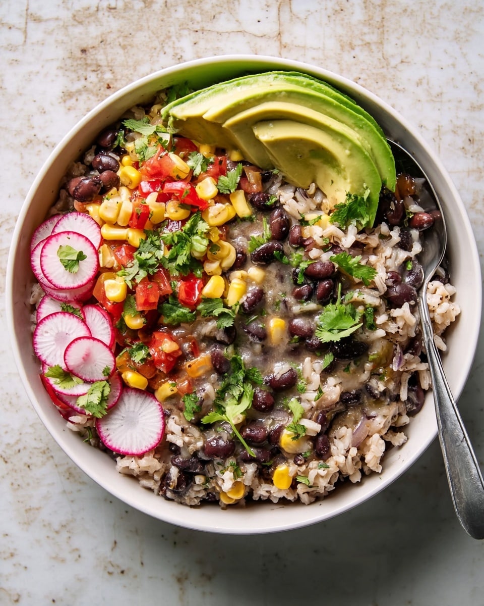 A white bowl filled with a layered dish starting with a base of cooked rice mixed with black beans, creating a speckled dark and light pattern. On top, there is a scattering of diced red tomatoes, yellow corn kernels, small pieces of green chili, and finely chopped herbs. Thin, circular slices of radish with white centers and red edges are placed around the bowl’s sides. A large, smooth slice of bright green avocado leans against the inner edge of the bowl. The dish is garnished with fresh green cilantro leaves. A silver spoon rests inside the bowl on the right side, with its handle sticking out. The bowl sits on a white marbled textured surface. Photo taken with an iphone --ar 4:5 --v 7