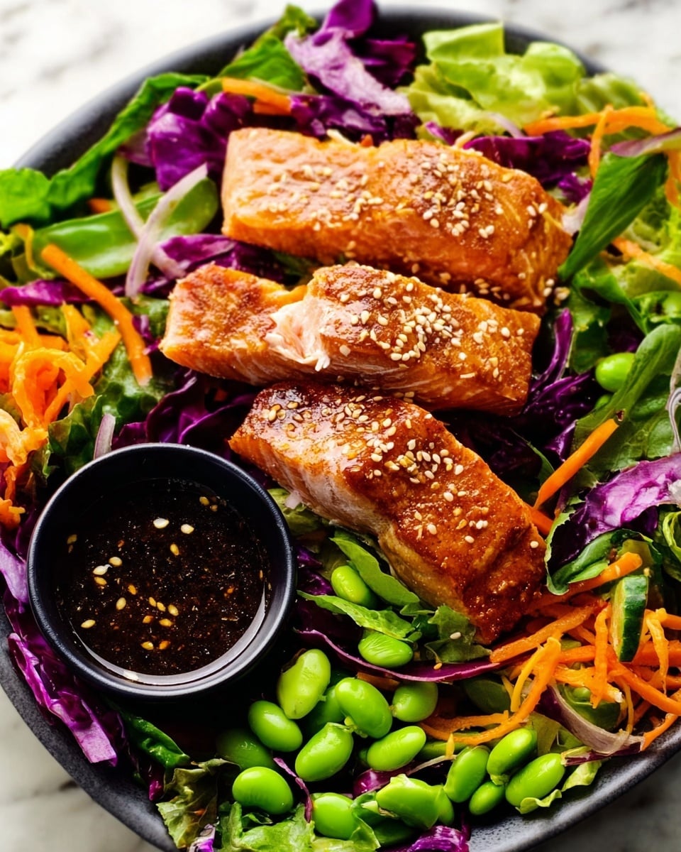 The image shows a dish with two main layers: at the bottom, there are mixed fresh salad greens including green lettuce and purple cabbage, thin orange carrot sticks, sliced red onion rings, and green edamame beans scattered around. On top of this bed of vegetables, there are several pieces of cooked salmon with a golden-brown color and sesame seeds sprinkled on top. To the side of the salmon, a small black bowl filled with dark sesame sauce with visible sesame seeds sits among the vegetables. The whole dish rests on a white marbled texture surface. photo taken with an iphone --ar 4:5 --v 7