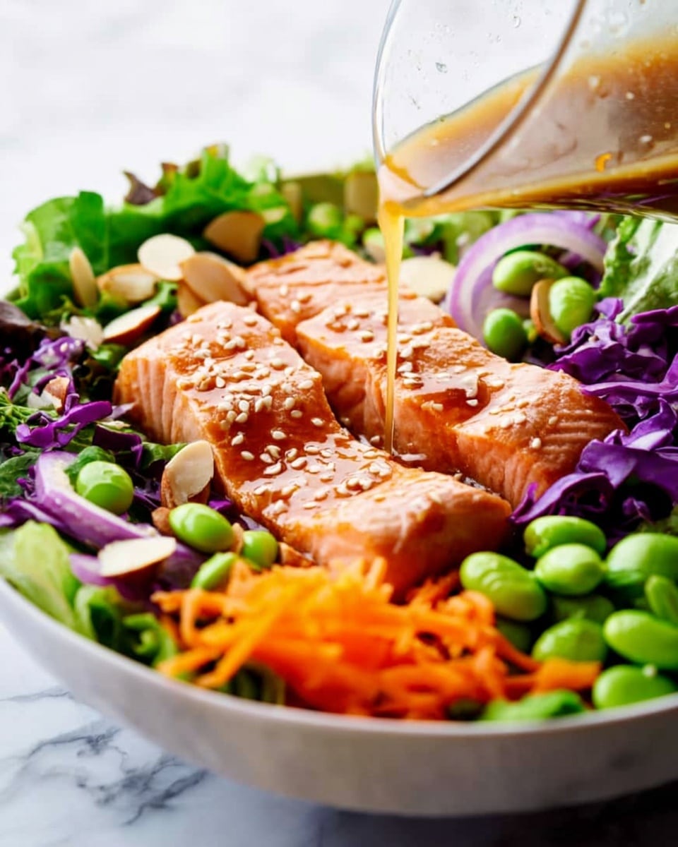 A white bowl filled with a colorful salad is shown on a white marbled surface. At the base, there is a mix of green leafy lettuce and purple cabbage, providing a rough texture and vibrant colors. On top, bright orange shredded carrots add a thin, soft layer along the bottom edge. In the central area, three pieces of cooked salmon with a pinkish-orange hue are arranged side by side, each piece covered with light brown sesame seeds and a shiny glaze. Scattered around the salmon are green edamame beans, almond slices, and a few onion rings in light purple and white, adding contrast and varied textures. A clear glass container positioned at the top right pours a light brown dressing that drips onto the salmon, creating a glossy wet effect. Photo taken with an iphone --ar 4:5 --v 7