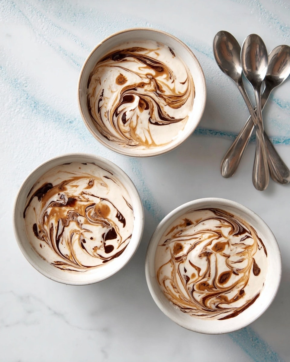 Three white bowls are filled with a creamy white dessert topped with a dark brown swirl pattern, likely chocolate or caramel, creating a marbled effect on the surface. Each bowl has a smooth, slightly thick texture of the dessert, with the swirl designs differing slightly in size and shape, showing fluid, curved lines and spots. The bowls are placed on a white marbled texture that enhances the clean and bright look of the setup. At the top right corner, there are four metallic spoons laid out casually, adding a touch of rustic charm to the scene. photo taken with an iphone --ar 4:5 --v 7